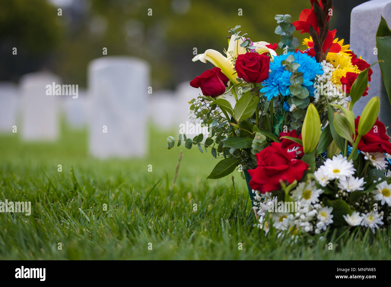 Weiße Grabsteine und Blumen am Friedhof für Memorial Day Stockfoto