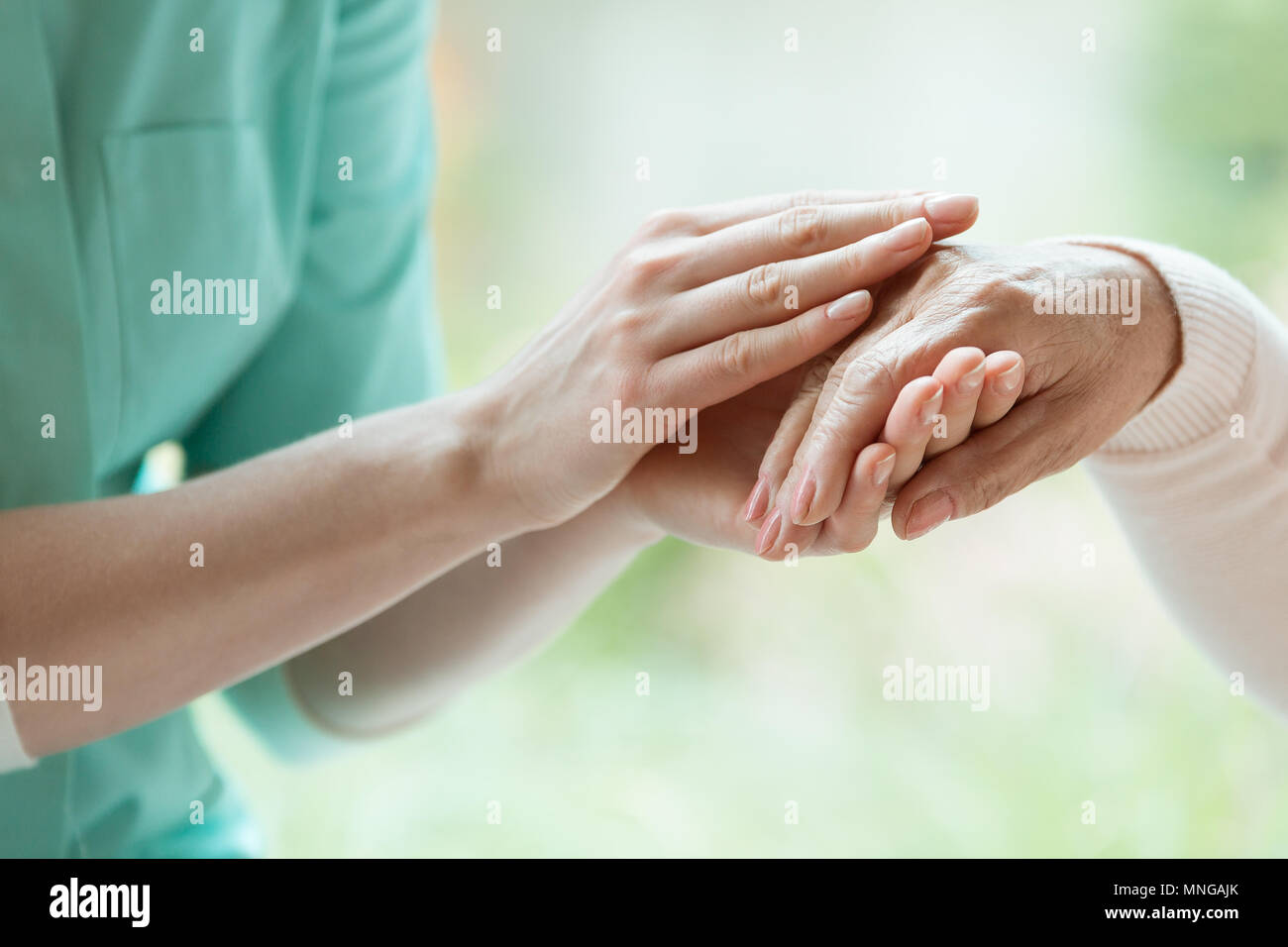 Junge Hausmeisterwohnung massieren Rentner hand mit Parkinson Stockfoto