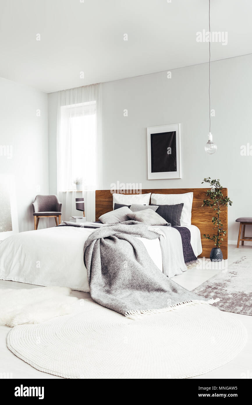 Weißer Teppich und King size Bett mit grauen Betten in geräumigen und  hellen Schlafzimmer mit dunklen Poster Stockfotografie - Alamy