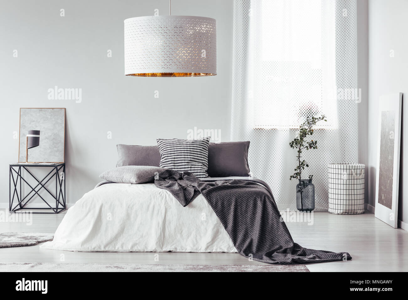 Gemusterte Decke und Kissen auf dem Bett und Tisch in Designer Schlafzimmer  Einrichtung mit weißen Lampe und Fenster Stockfotografie - Alamy