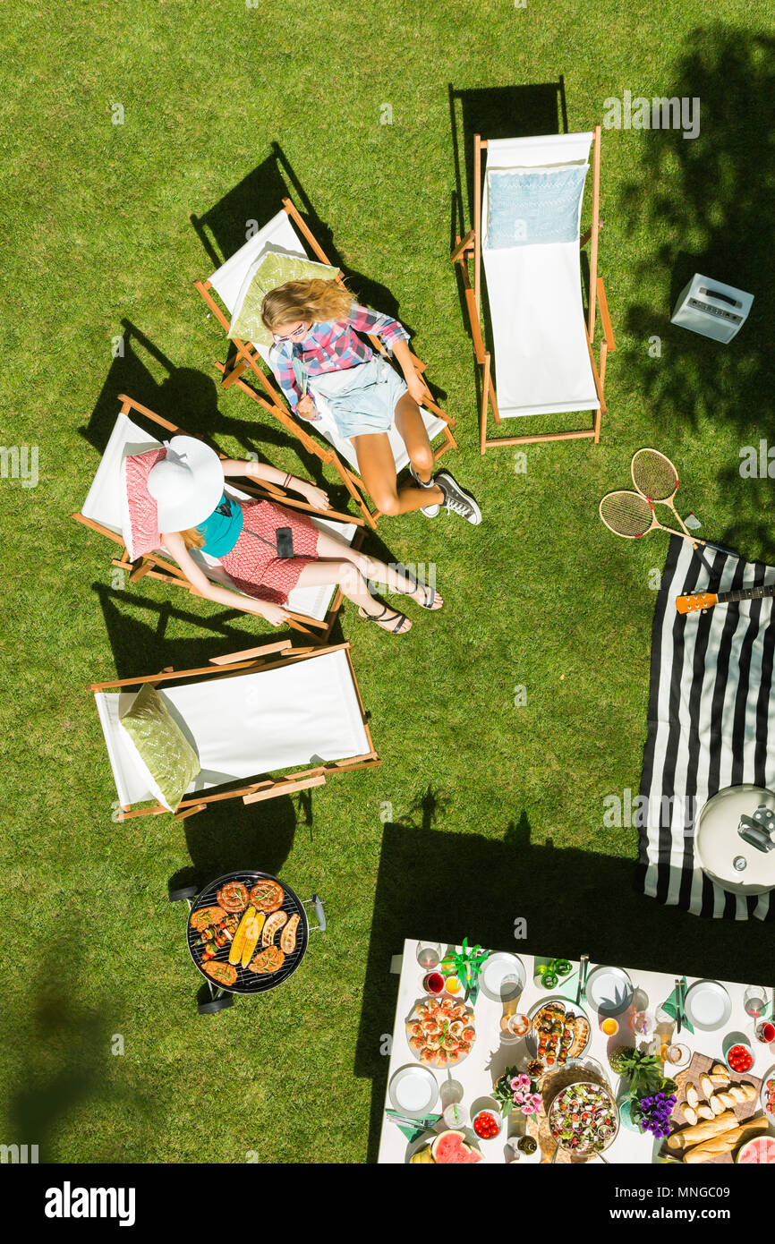 Blick von oben auf die Frauen liegen auf den Liegestühlen im Garten Stockfoto