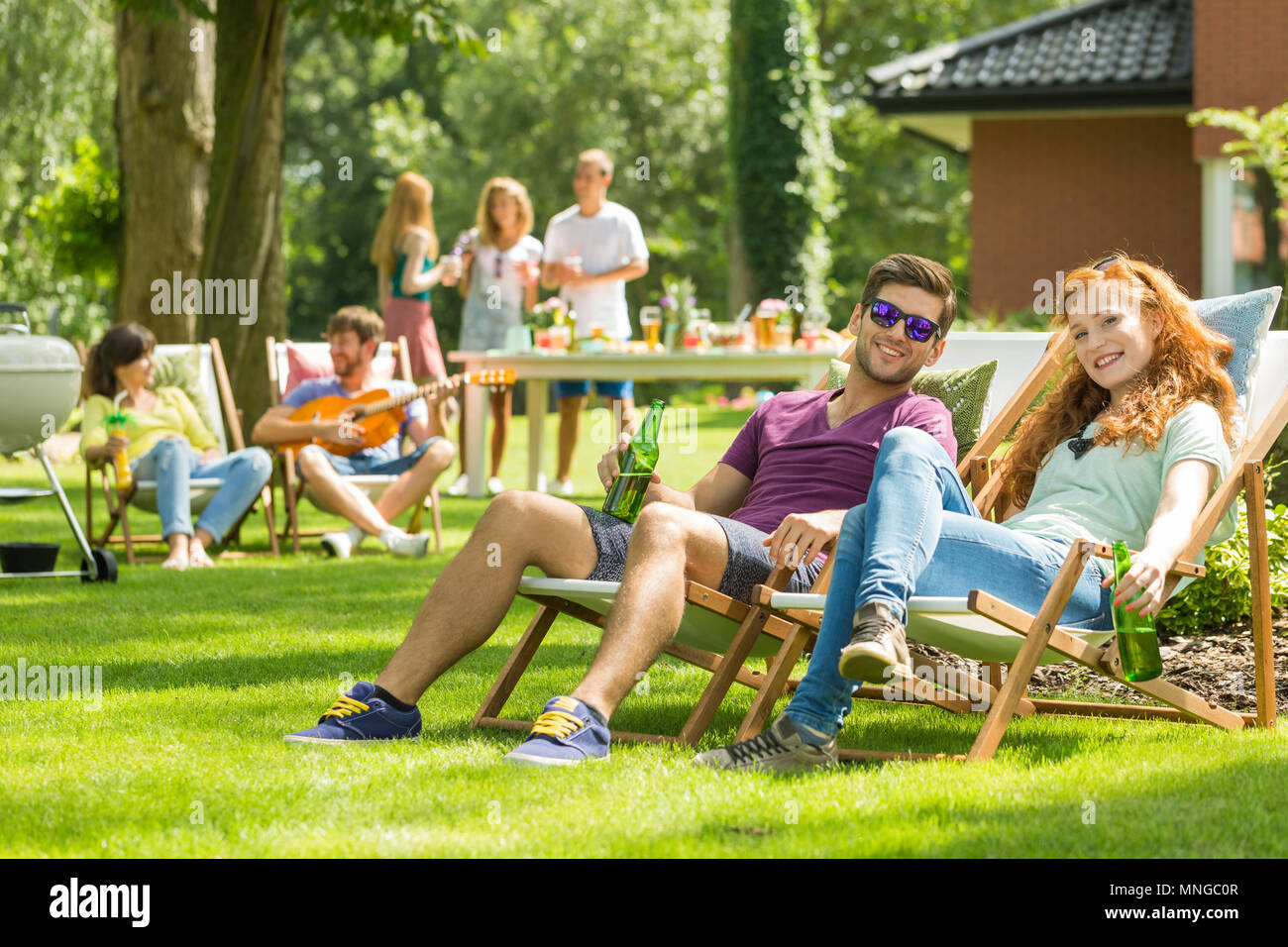 Junges Paar sitzen auf den Liegestühlen im Garten party Stockfoto