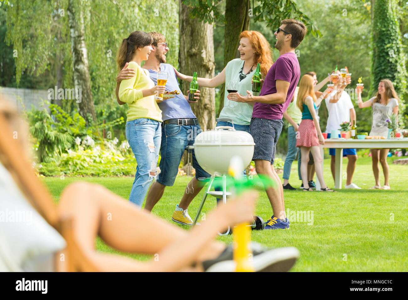 Junge Menschen Grillen und trinken in Garten Stockfoto