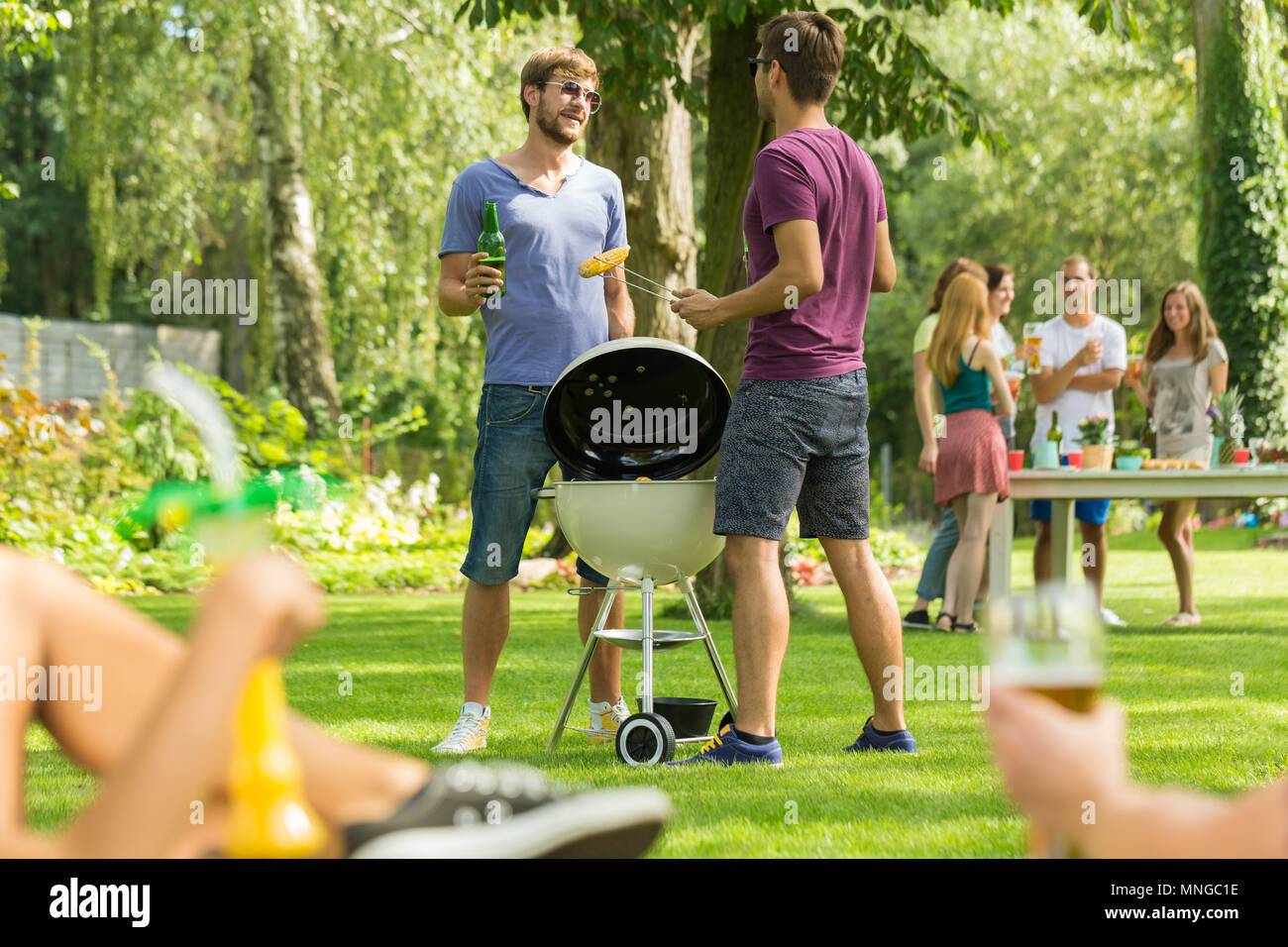 Zwei Männer standen neben Grill im Garten Stockfoto