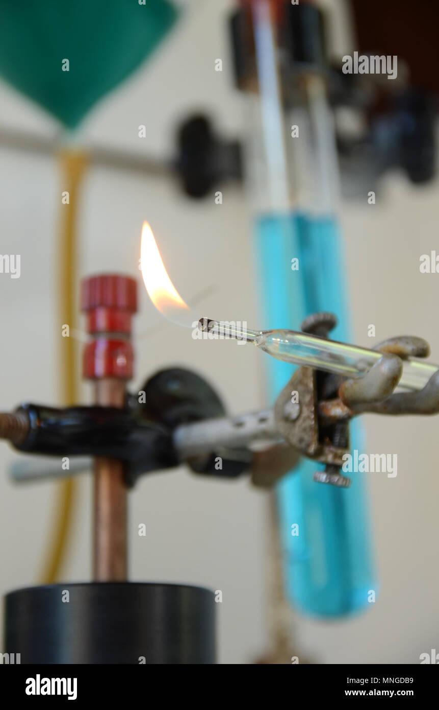 Flamme brennen aus einem Glasrohr mit Laborgeräten als diffuser Hintergrund. Stockfoto
