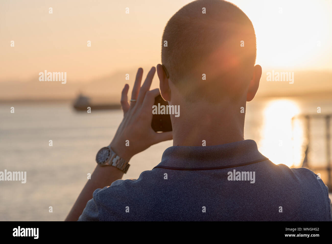 Rückansicht des Menschen nach oben smart phone mobile Kamera ein Foto von Elliott Bucht bei Sonnenuntergang zu nehmen. Stockfoto