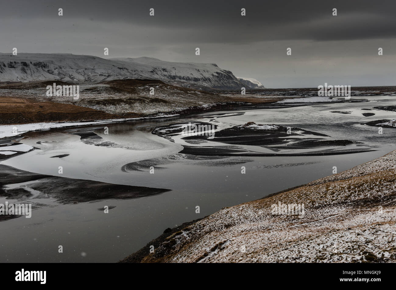 Smowy Wetter mit dunklen Wolke Himmel an einem Schwarzen geschliffen Riverbed in isländischer zurück Land bedeckt, April 2018 Stockfoto