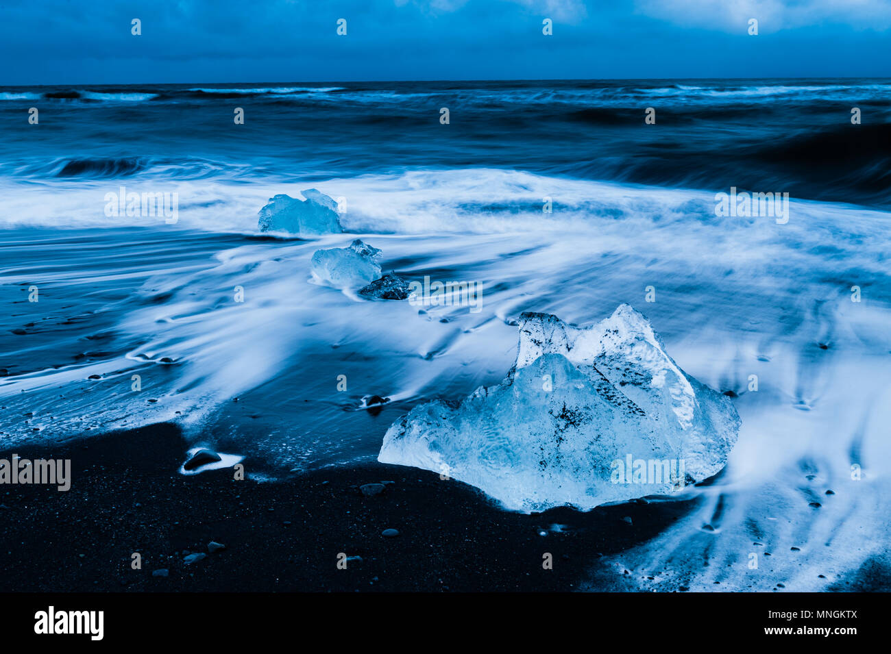 Eis Felsen durch die kommende Brandung des Atlantik an der schwarzen vulkanischen Sand gewaschen im Diamond Beach, Island april 2018 Stockfoto