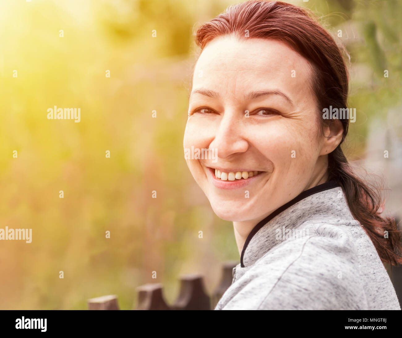 Glückliche junge Frau mit natürlichen Haut in der Natur. Portrait von Frau mit natürlichen Haut, kein Make-up, in die Kamera schaut Stockfoto