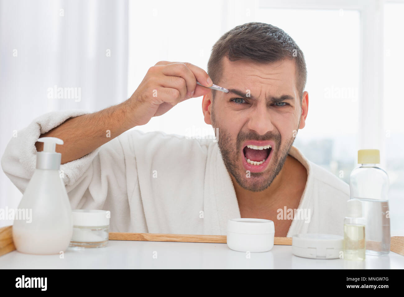 Freudige netter Mann Zupfen der Augenbrauen Stockfoto