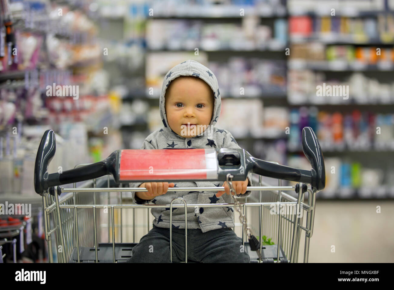 Kleinkind baby boy, sitzen in einem Einkaufswagen im Supermarkt, lächelnd  und Brot aß, während Mami einkaufen ist Stockfotografie - Alamy