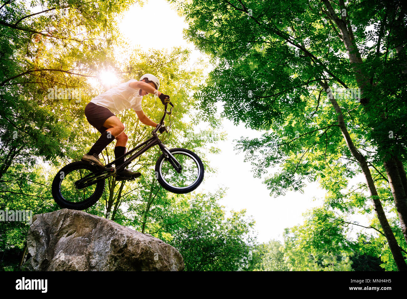 Junge Athlet Tricks auf seinem Versuch Fahrrad in einem Felsen im Wald Stockfoto