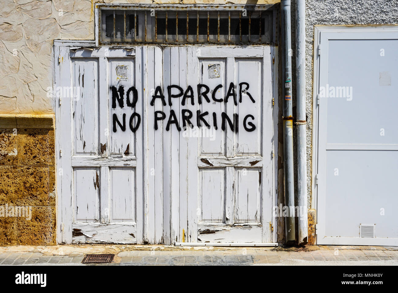 Die Türen auf spanischem Grundstück sind abblätternd weiß lackiert und es gibt keinen Aparcar, keine grob lackierten Parkplätze. Guardamar del Segura. Übersetzung Stockfoto