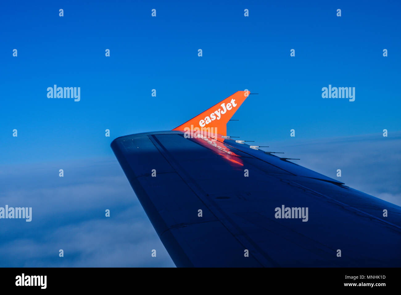 EasyJet-Schriftzug auf der Winglet mit Flügelspitze im Jet-Flugzeug bei Sonnenaufgang. Flügel im Schatten. Über Wolken im blauen Himmel. Fluggesellschaft, Flugzeug Stockfoto