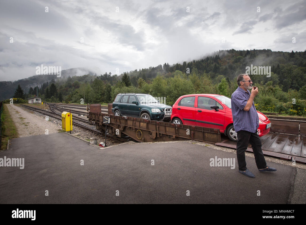 Mann Rauchen einer Pfeife, während sie darauf warteten, dass Auto Zug autoverlad Route zwischen Bohinjska Bistrica und die meisten na Soci, Slowenien abzuweichen. Stockfoto