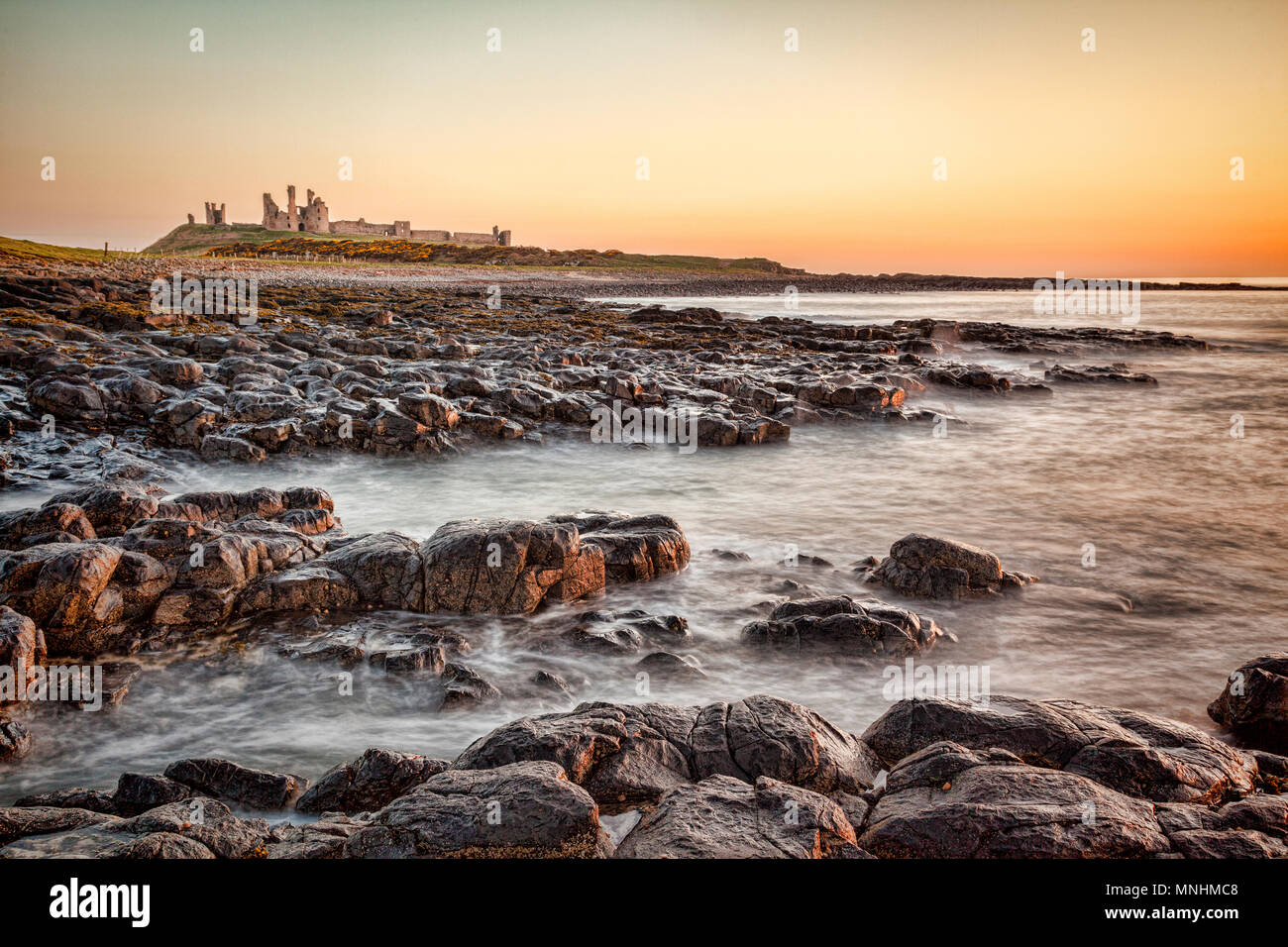 Sonnenaufgang am Dunstanburgh Castle auf der Northumberland Küste, North East England. Stockfoto