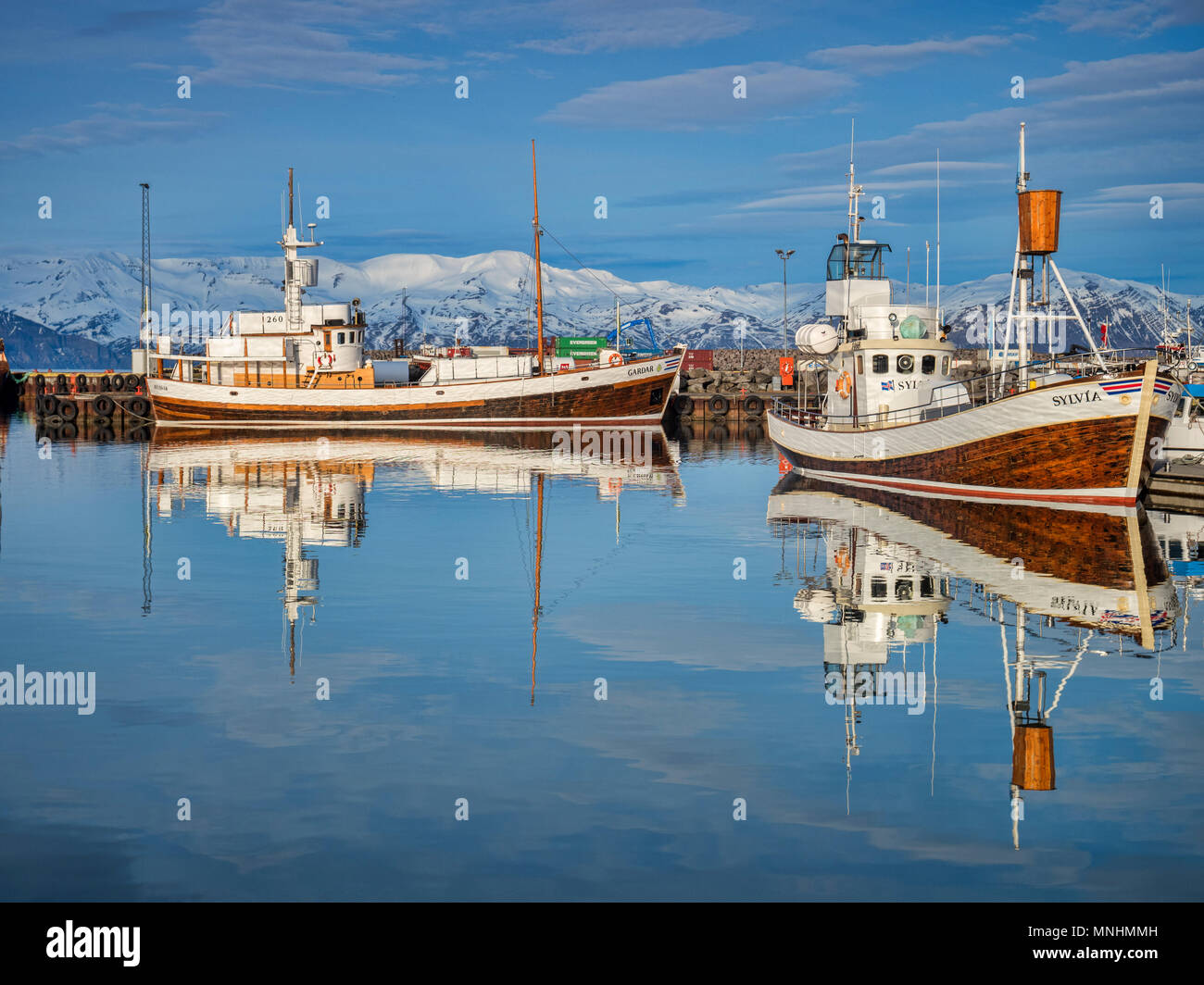 13. April 2018: Husavik, Island. Der Hafen in Husavik im Norden Island, mit Whale-watching Schiffe im ruhigen Wasser wider. Stockfoto