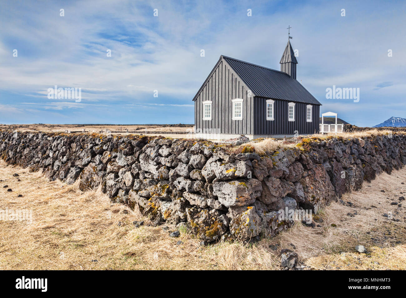 Budir Kirche, wie die Kleinen Schwarzen Kirche bekannt, auf der Halbinsel Snaefellsnes, West Island, mit einer Trockenmauer aus Lava. Stockfoto