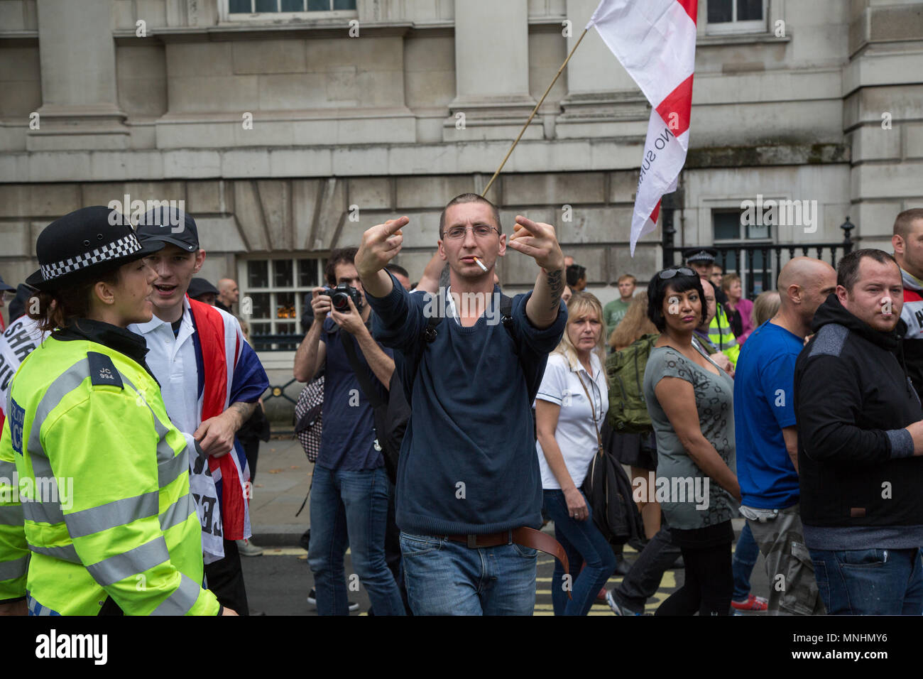 Ein Mann seine Finger auf, der während einer EDL März in Whitehall wird erzählt von einer Polizistin zu stoppen Stockfoto