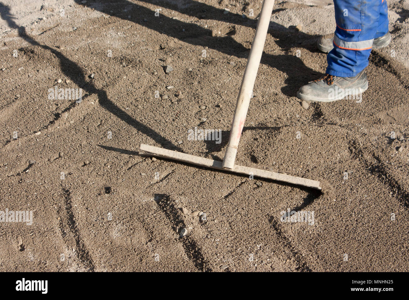 Straße Baustelle: Straße pflastern Vorbereitung, Arbeiter Abflachung der Sand in motion blur Stockfoto