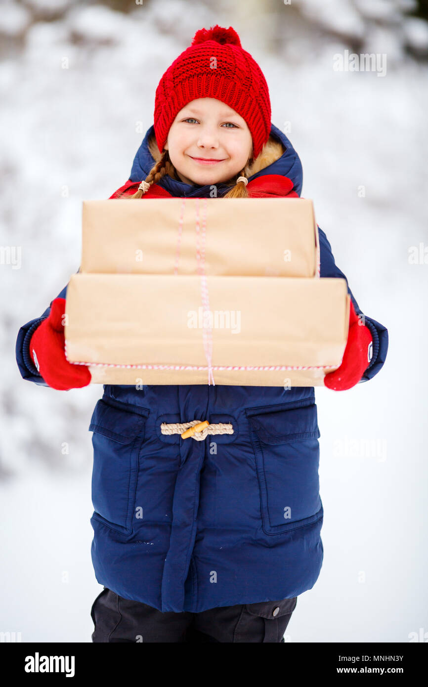 Adorable kleine Mädchen mit warmer Kleidung im Freien am Weihnachtstag holding Geschenke Stockfoto
