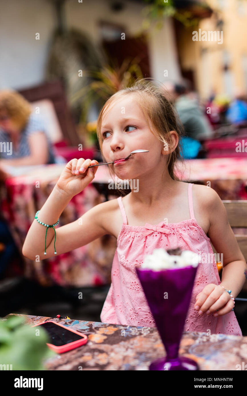 Adorable kleine Mädchen im Café draußen Eis essen im Sommer Tag Stockfoto