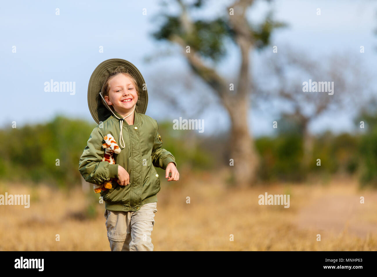 Adorable kleine Mädchen in Südafrika Safari im Busch mit Giraffe toy läuft Stockfoto