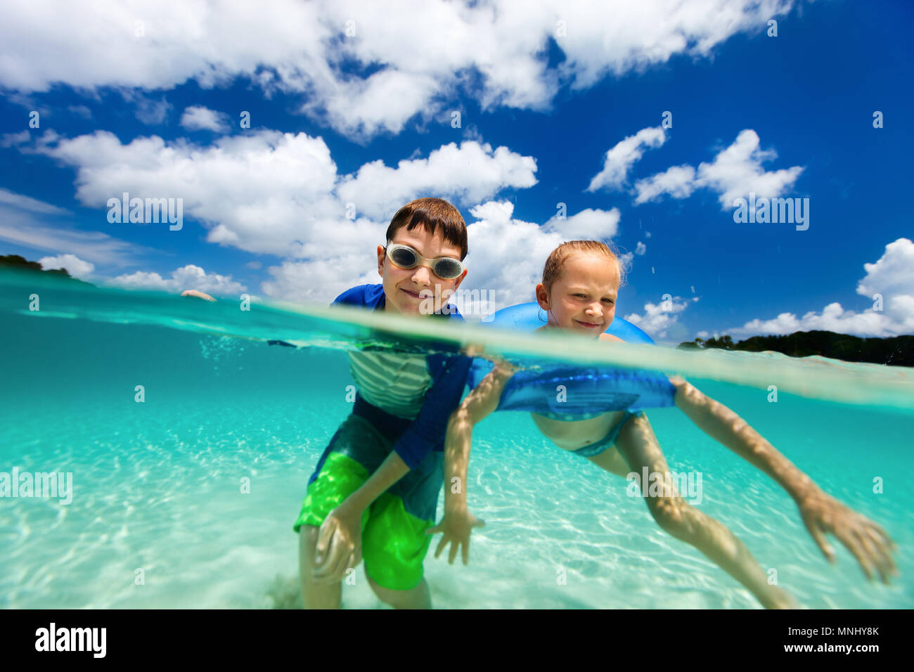 Split Unterwasser Foto der Zicklein, die süßen kleinen Mädchen und niedlichen Jungen planschen in einem tropischen Meer Wasser in den Sommerferien Stockfoto