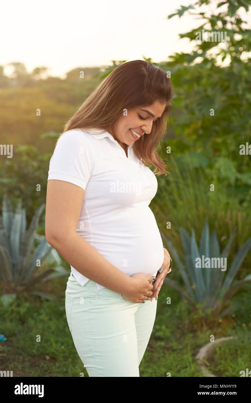 Hispanic Frau in Schwangerschaft stehen auf Natur Hintergrund Stockfoto