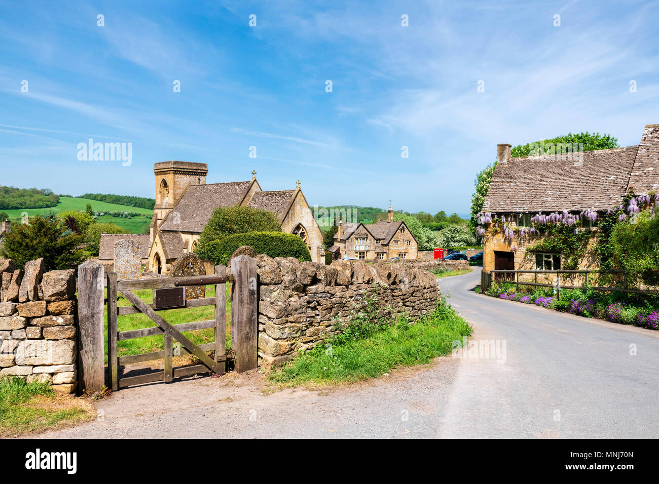 Snowshill, Cotswolds, England, UK. Wisteria Blumen auf einem Haus neben der Kirche in einem Cotswold Village. Stockfoto