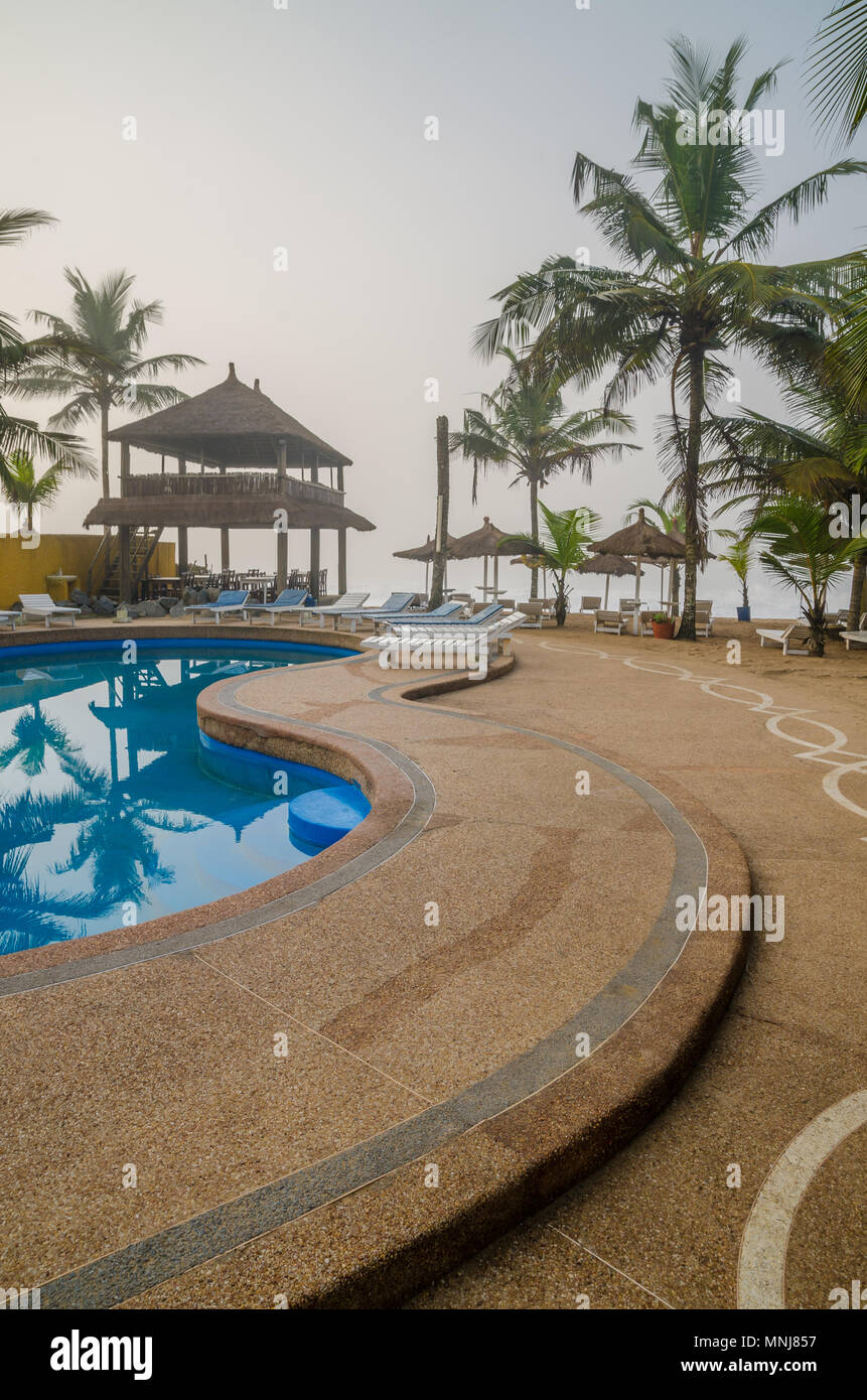 Ferienanlage mit Pool, Palmen und strohgedeckten Hütten an der Küste Stockfoto