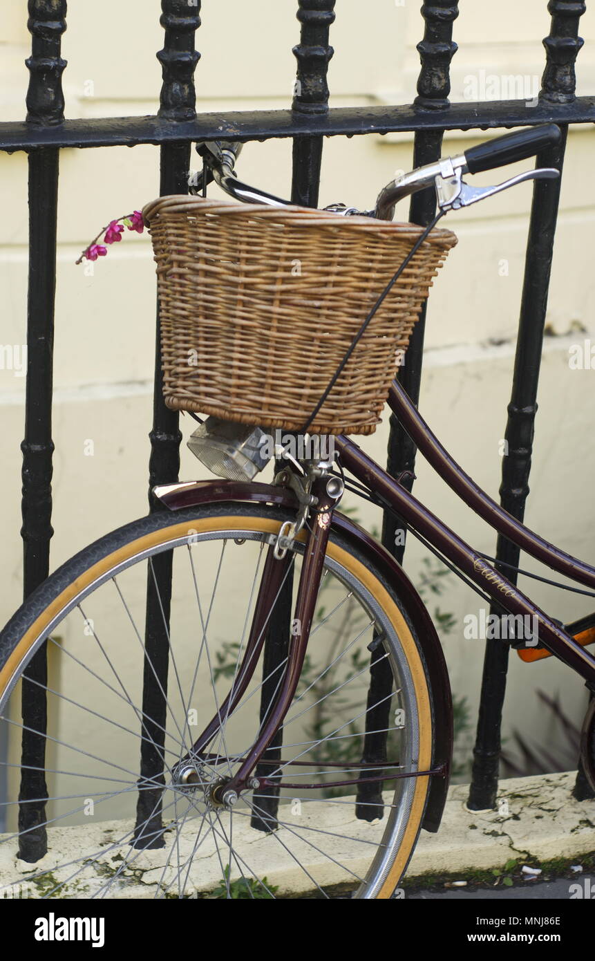 Altmodische Fahrrad mit Korb ruhenden gegen schwarze Geländer in Brighton, UL. Stockfoto