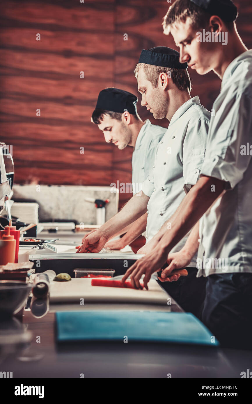 Die Köche kochen köstliches Sushi im modernen Restaurant. Die Profis am Werk. Moderne, voll ausgestattete Küche. Mod int Stockfoto