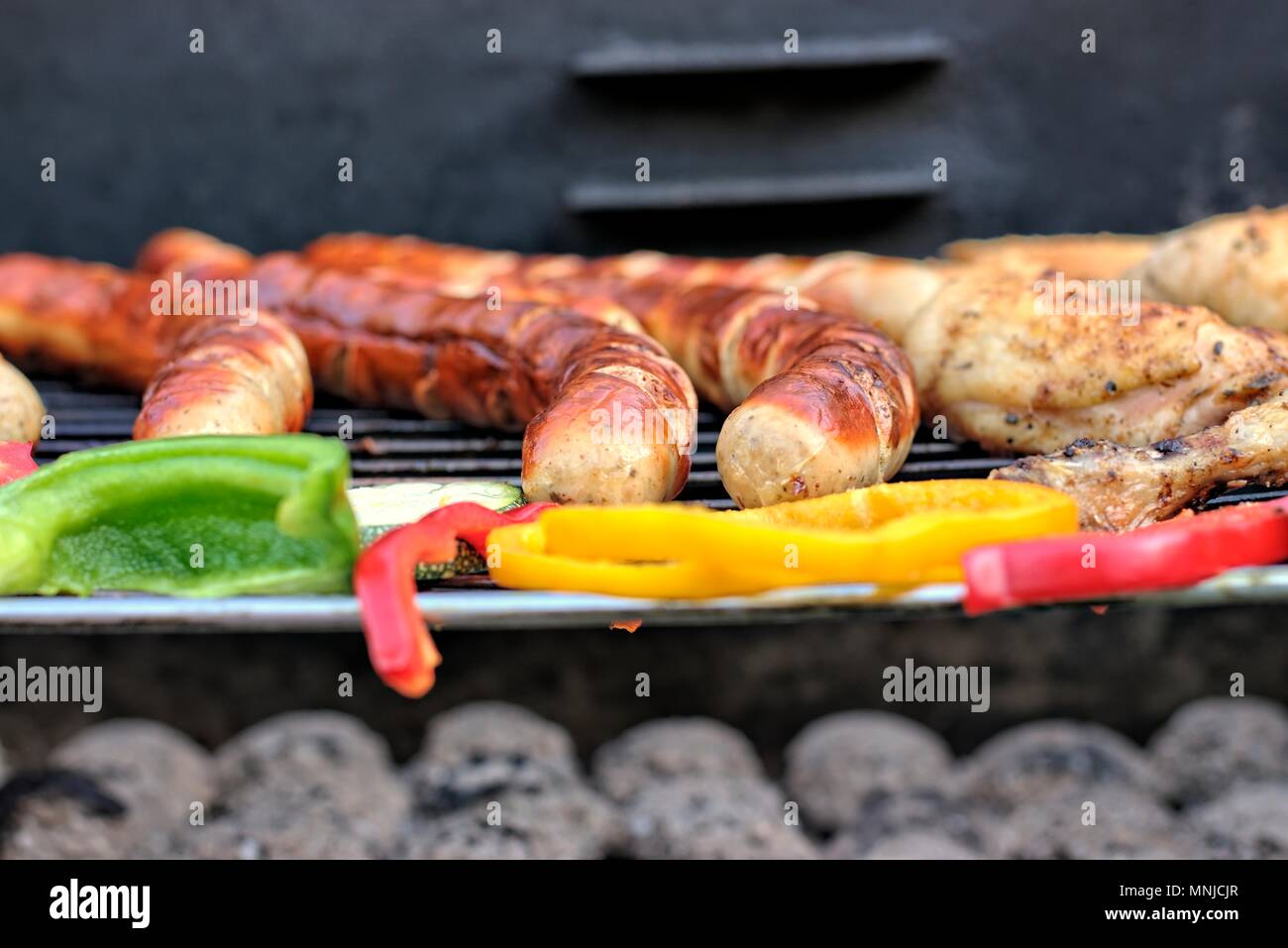 Leckeres Essen, Ernährung, kulinarischen und Grill Konzept: gegrillte Würstchen, Hähnchen Schenkel und Gemüse auf einem Grill. Stockfoto