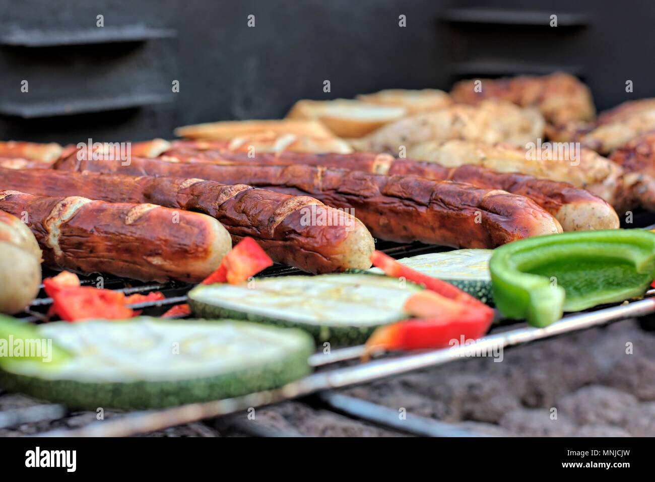 Leckeres Essen, Ernährung, kulinarischen und Grill Konzept: gegrillte Würstchen, Hähnchen Schenkel und Gemüse auf einem Grill. Stockfoto