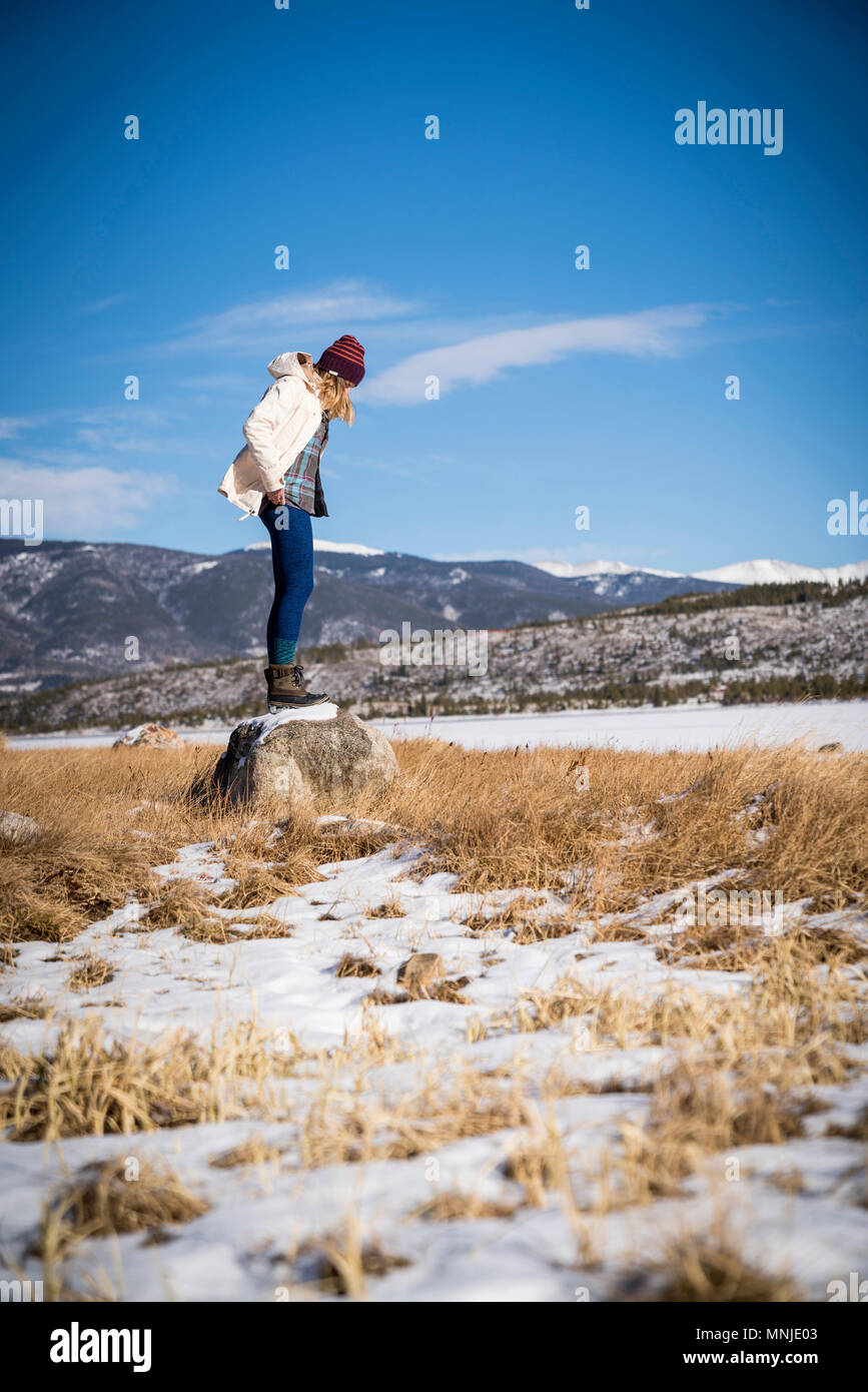 Junge Frau steht auf Rock an sonnigen Wintertag in Colorado, USA Stockfoto