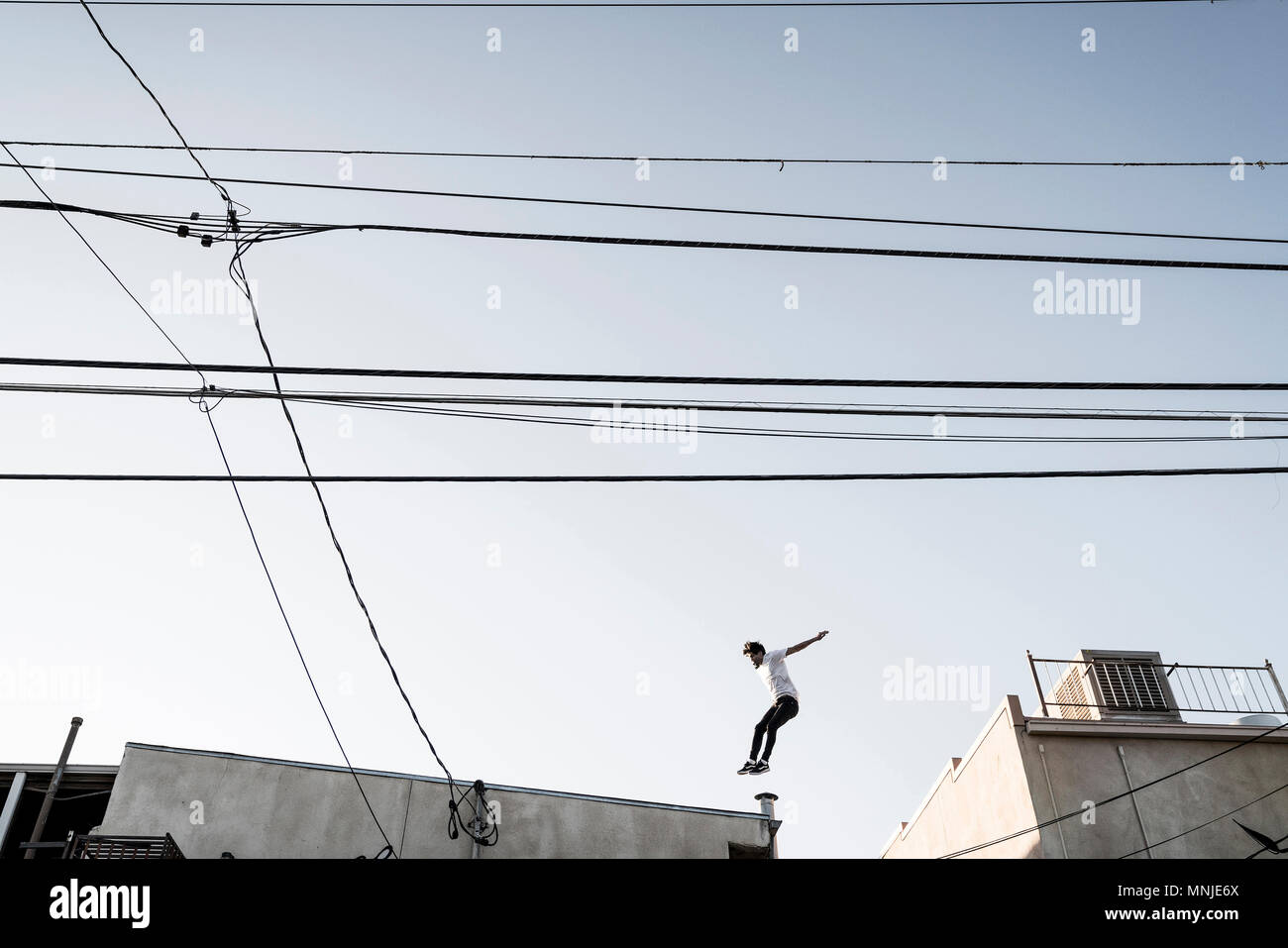 Seitenansicht von Parkour Athlet in der Luft, während zwischen den Dächern, Denver, Colorado, USA Stockfoto