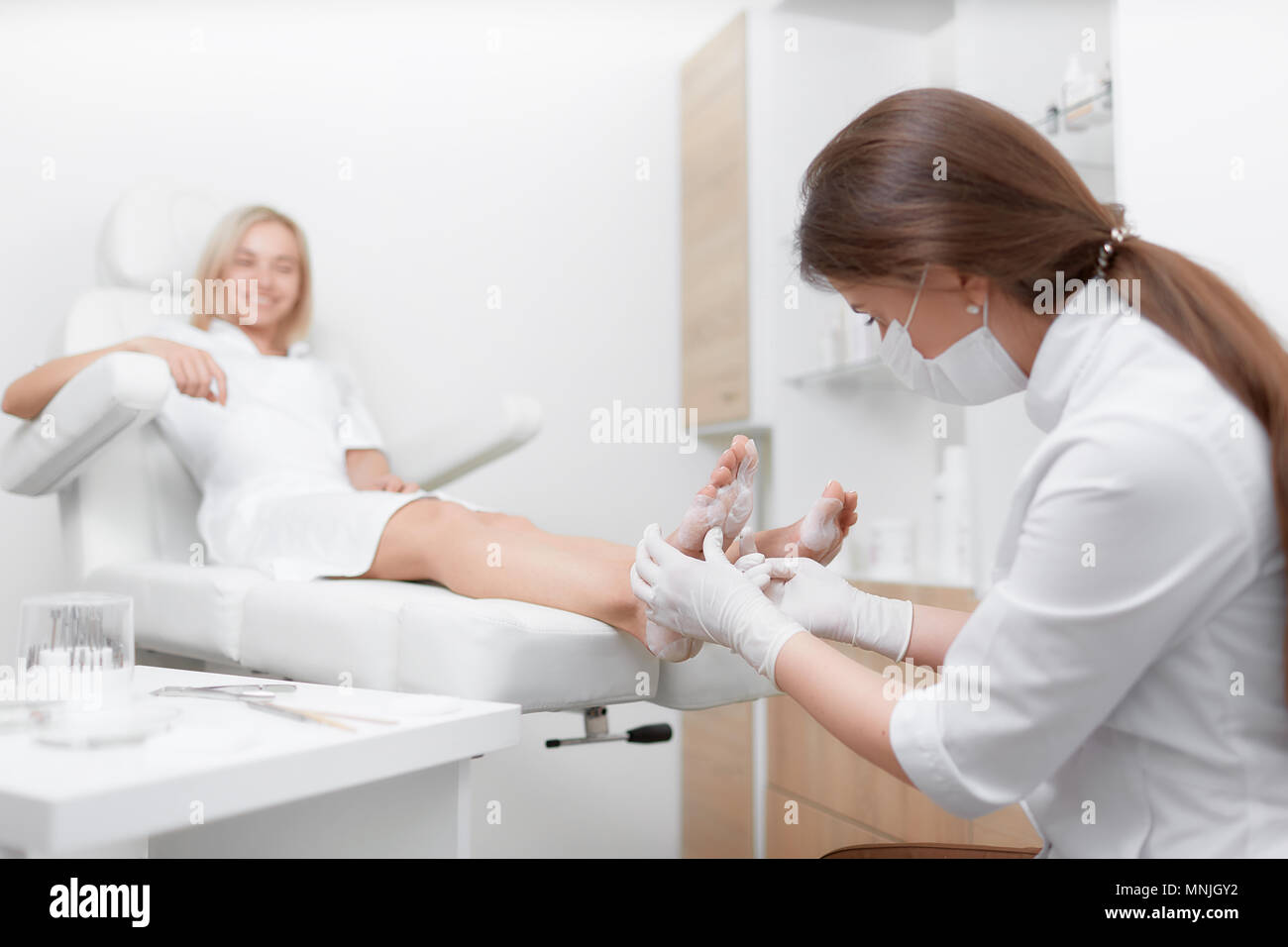 Fußarzt Ärztin Verfahren der Massage und Peeling. Stockfoto