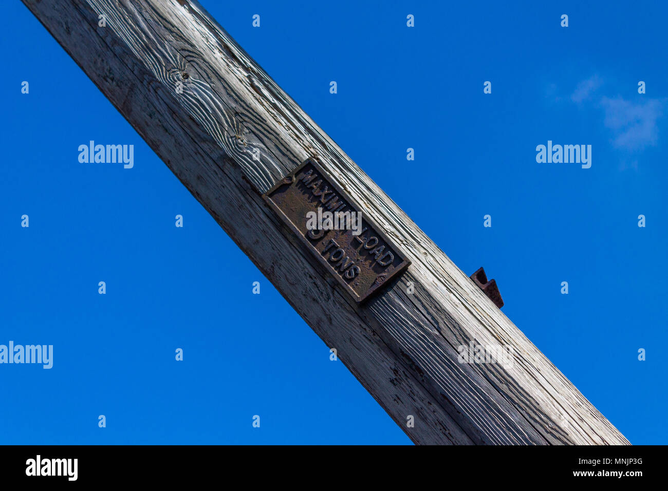 Gusseisen Zeichen auf einem alten hölzernen Kranausleger oder Ausleger mit einer Traglast zeigt drei Tonnen oder 3 Tonnen, gegen ein strahlend blauer Himmel. Stockfoto