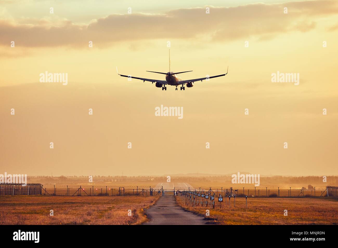 Airport Traffic auf den Sonnenuntergang. Flugzeug Landung auf der Landebahn. Stockfoto