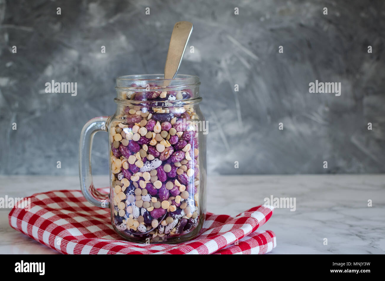 Sortiment von trockenen organischen Bohnen und Linsen aus Glas Glas auf Marmortisch. Vielzahl an raw Hülsenfrüchte. Ausgewogene Ernährung, Kochen, vegetarische und sauber Essen Stockfoto
