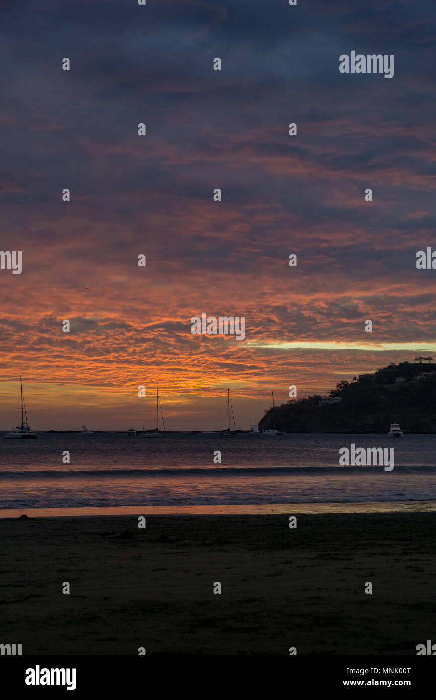 Bunte Wolken bei Sonnenuntergang am Strand mit Booten. San Juan del Sur, Nicaragua. Stockfoto