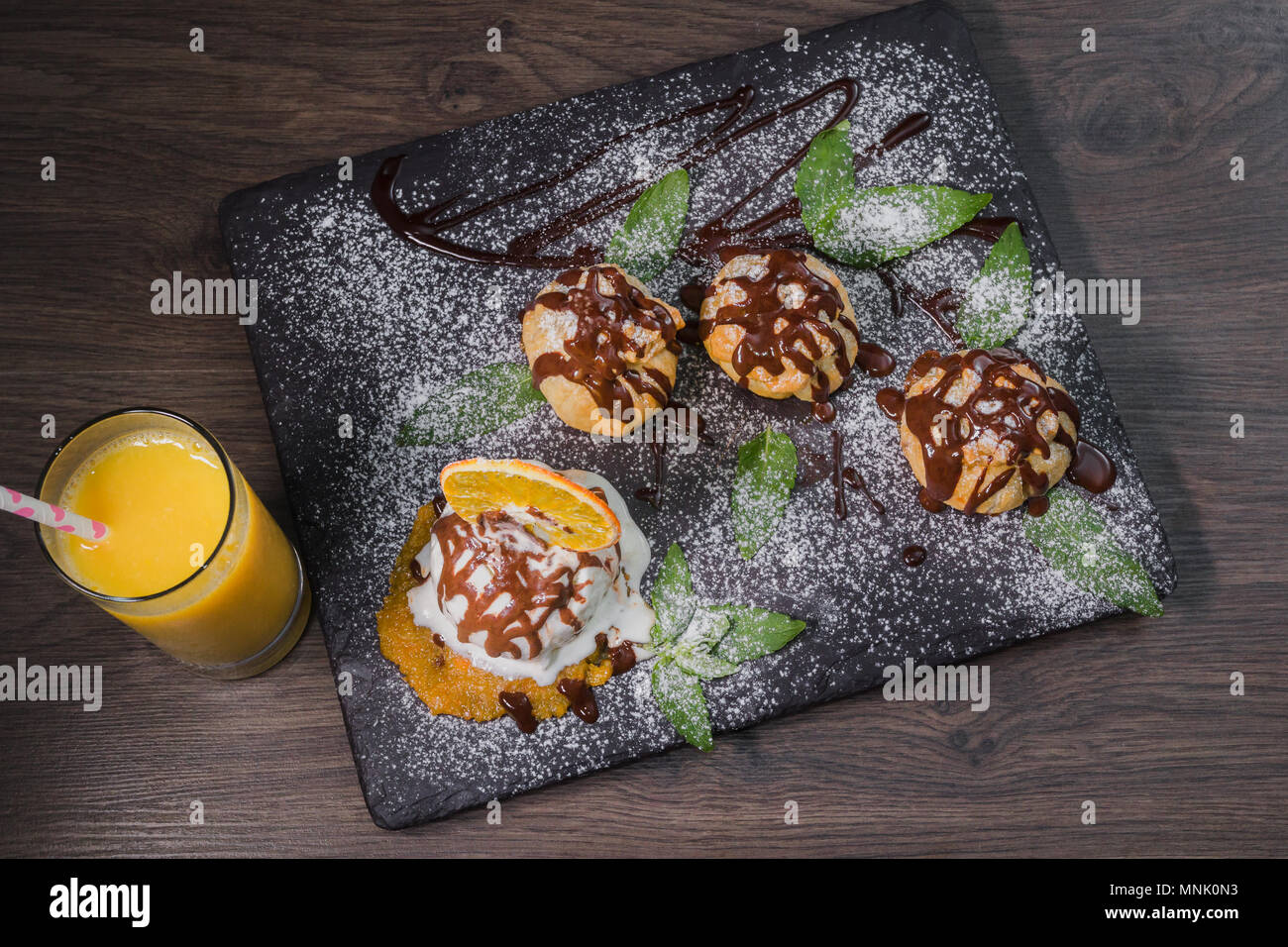 Eine Kugel Eis auf einem Stein mit einem orangefarbenen Glas Saft Stockfoto