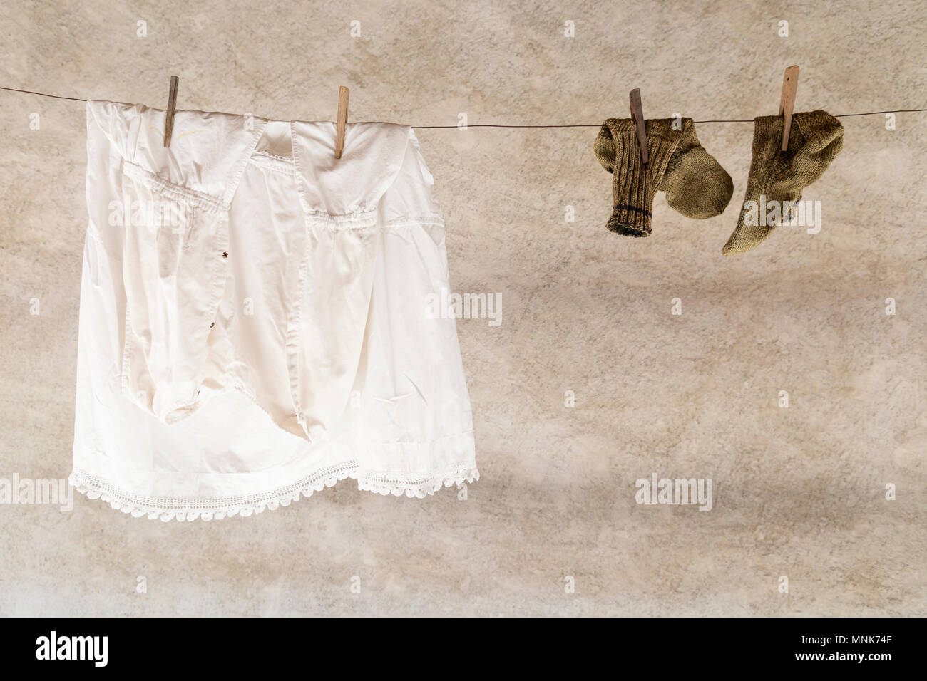Ein weißes Hemd und ein Paar gestrickte Wollsocken hängend an einem Seil mit Wäsche Wäscheklammern aus Holz Stockfoto