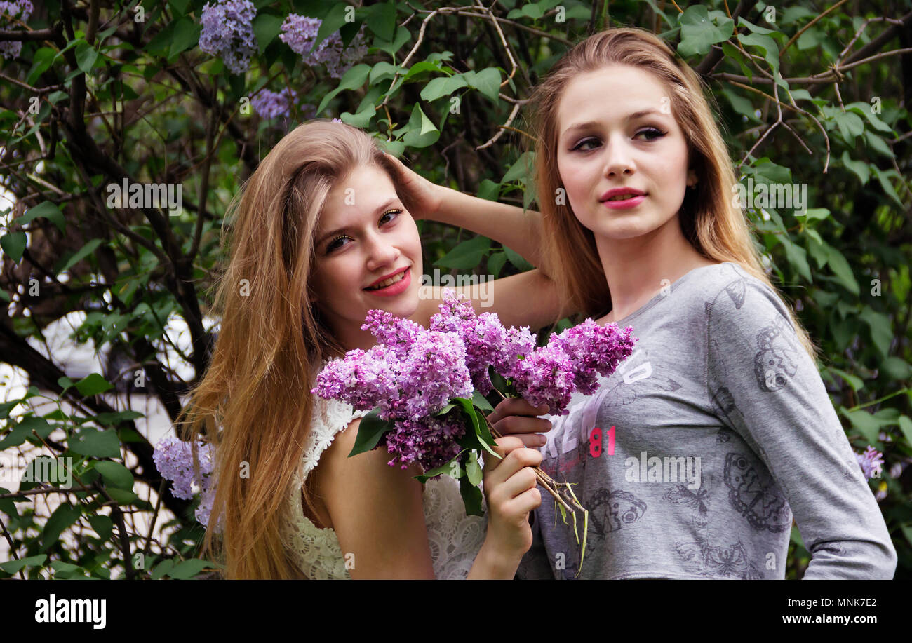 Zwei schöne und niedliche jugendlich Mädchen in blühender Flieder. Stockfoto