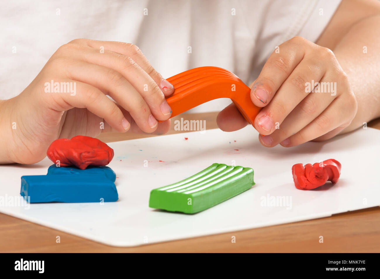 Die Hände des Kindes Spritzgießen von farbenfrohen Ton, Plastilin auf dem Tisch Stockfoto