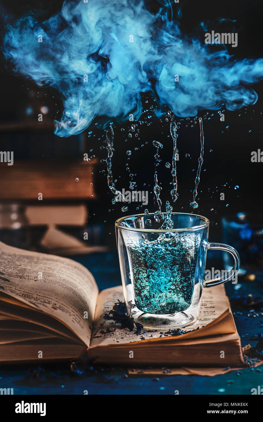 Doppelwand Glas Tasse blau Tee auf ein offenes Buch unter einem regen Wolke aus Dampf. Regenwetter lesen Konzept Stockfotografie