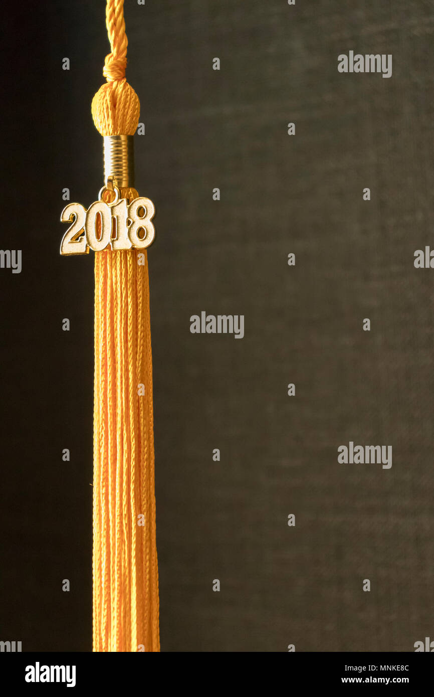 Klasse von 2018. Gold Quaste drop Graduierung kleid Zubehör und Andenken vor einem schwarzen Hintergrund. Iconic Symbol der akademischen Leistung. Vertikale. Stockfoto