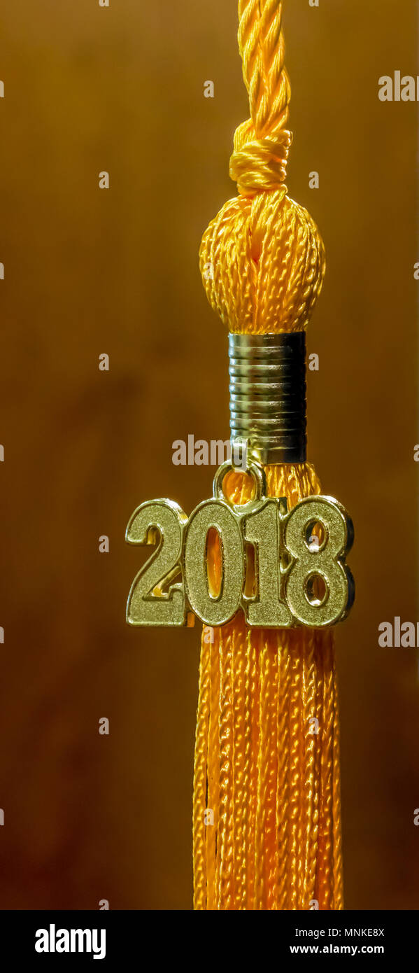 Klasse von 2018. Gold Quaste drop Graduierung kleid Zubehör und Andenken gegen einen braunen Hintergrund. Iconic Symbol der akademischen Leistung. Stockfoto
