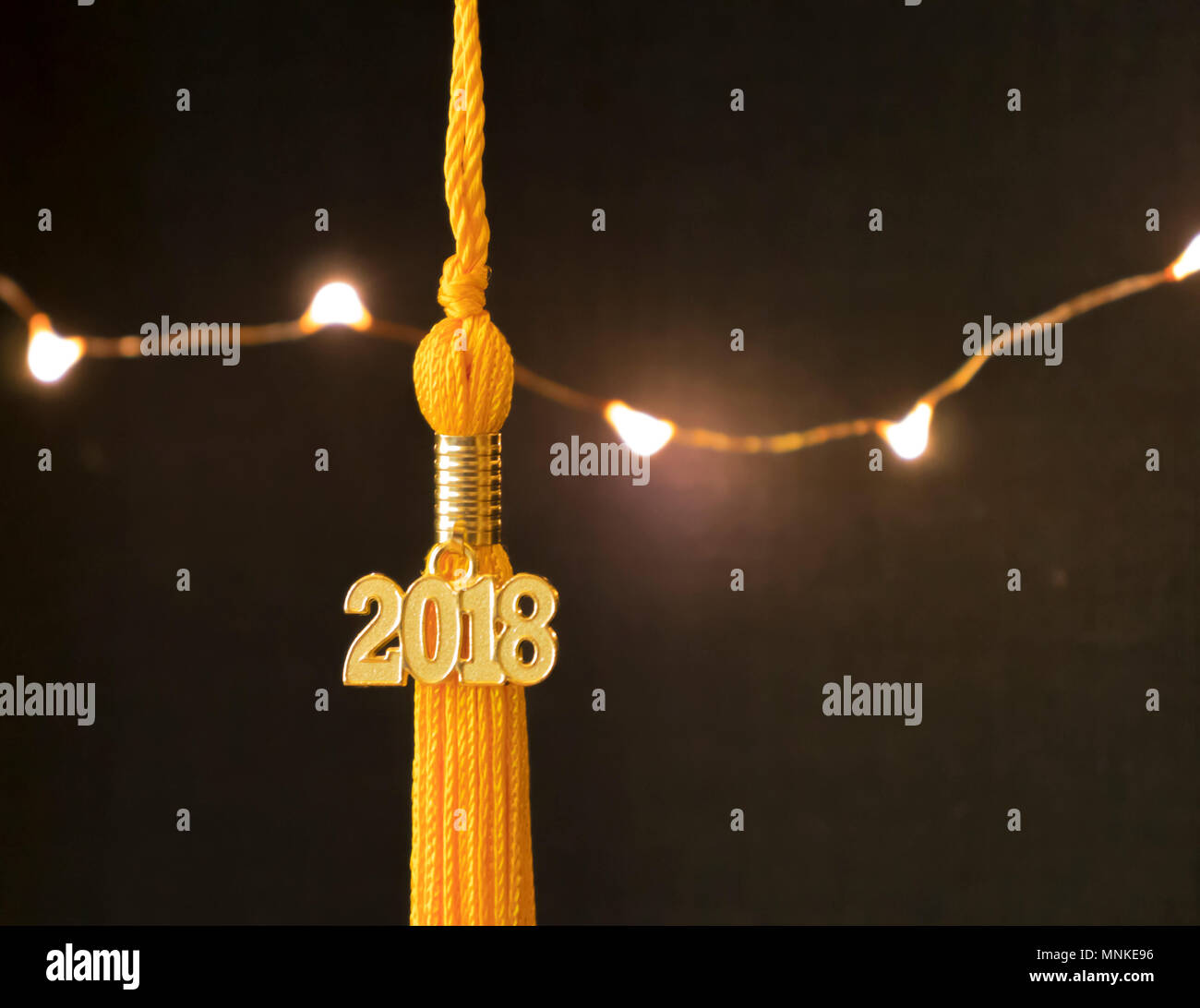 Klasse von 2018. Gold Quaste drop Graduierung kleid Zubehör und Andenken vor einem schwarzen Hintergrund und Leuchten. Iconic Symbol der akademischen Leistung. Stockfoto